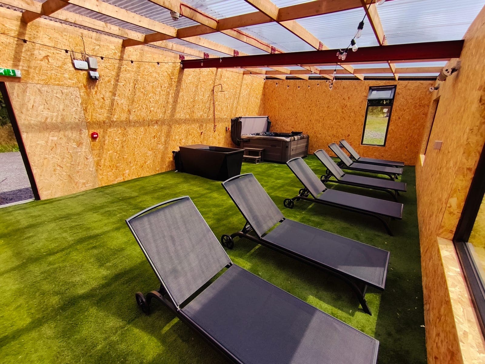 Loungers on the covered deck, hot tub and cold plunge behind