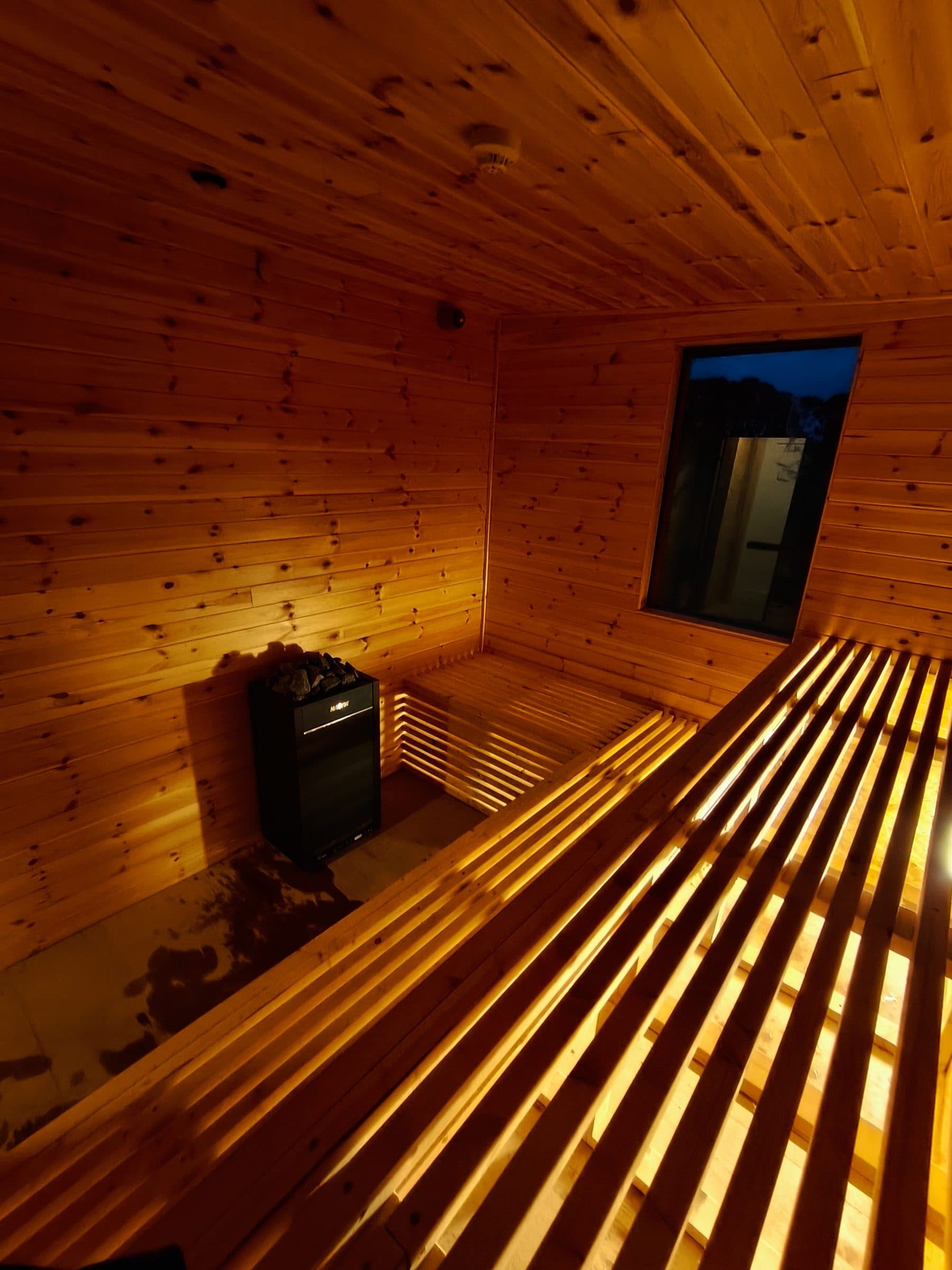 Canal View Lodges spa — inside the cedar sauna, heater and stones lit at dusk